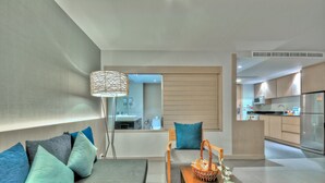 A modern living room with a sofa, a coffee table, and a floor lamp. There is a kitchen visible in the background. - ASHLEE Heights Hotel Patong (Patong)