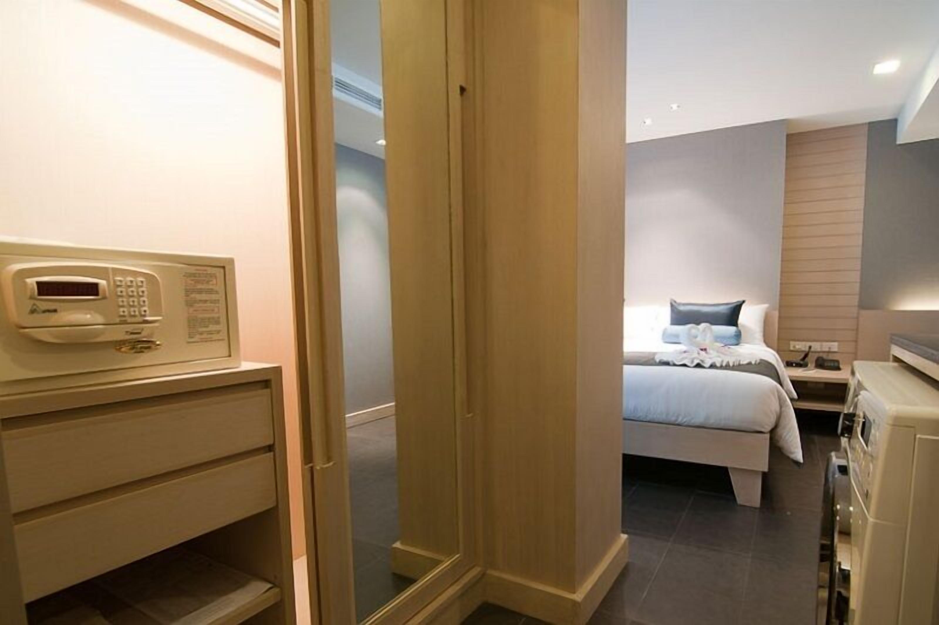 A hotel room with a bed, bedside table, and a microwave on a counter.