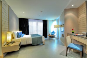 A modern hotel room with a bed, bedside table, desk, chair, and a view of the city. - ASHLEE Heights Hotel Patong (Patong)