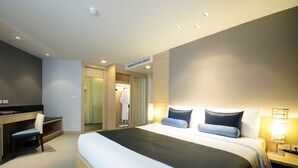 A modern hotel room with a large bed, a desk, and a chair. There is a robe hanging on the door, and a lamp on the bedside table. - ASHLEE Heights Hotel Patong (Patong)