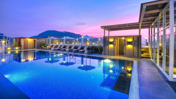 A modern hotel pool area with a clear view of the mountains in the background, a covered seating area, and a well-lit pool. - ASHLEE Heights Hotel Patong (Patong)