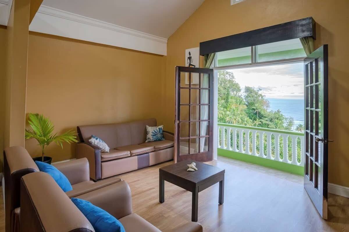 Una sala de estar con un sofá, una mesa de centro y vista al océano a través de un ventanal.