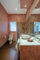 A modern bathroom with a large mirror, two sinks, a toilet, and a shower.