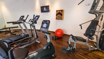 Une salle de sport équipée de tapis de course, de vélos elliptiques et de matériel de musculation.