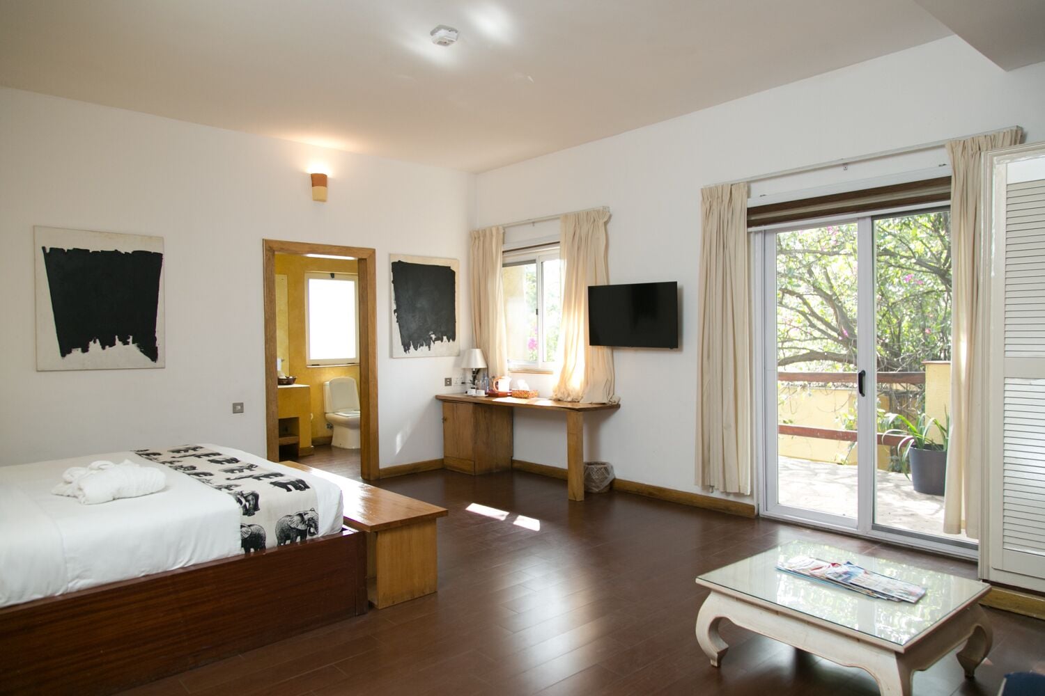 Ett hotellrum med en säng, ett skrivbord, en tv och en balkong med utsikt.