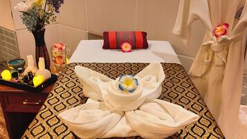 Experience ultimate relaxation in this serene spa room, featuring a massage table, decorative centerpiece, and soothing ambiance.