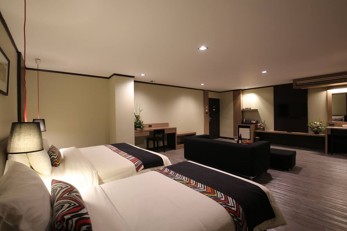 Une chambre d’hôtel avec deux lits, un bureau, un canapé et un grand miroir.