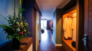 A hallway with a potted plant, a clothing rack, and a wooden bench. - Bangkok Inter Place Hotel (Bangkok)