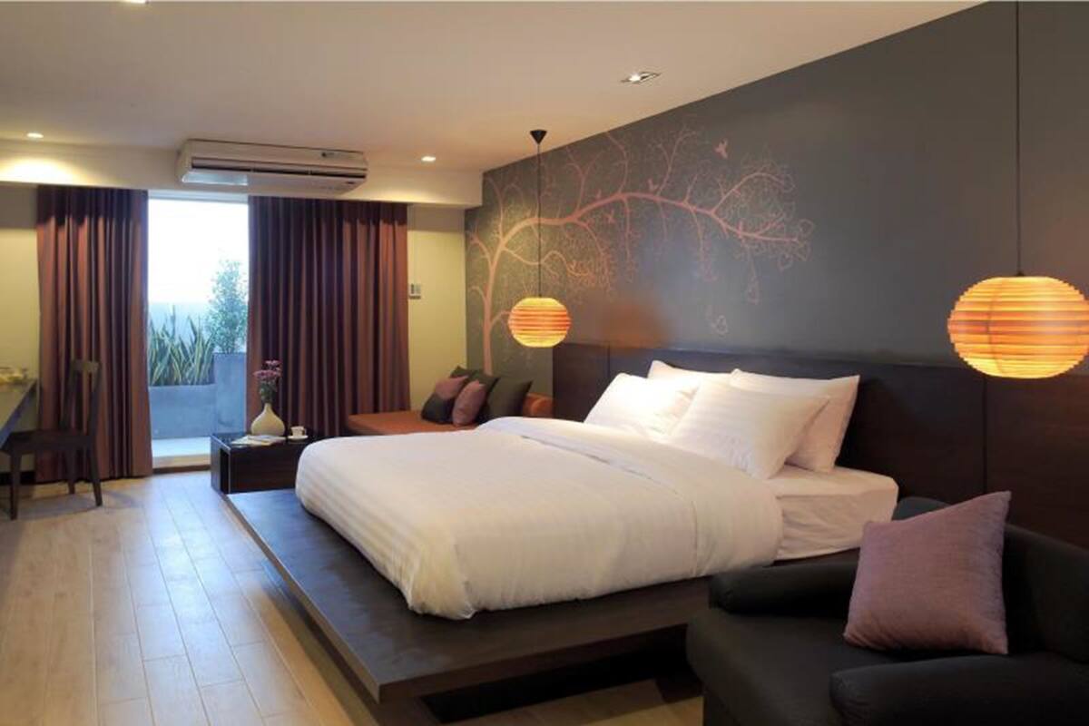 Une chambre d’hôtel moderne, dotée d’un grand lit, d’un canapé, d’un bureau et offrant une vue sur l’extérieur.