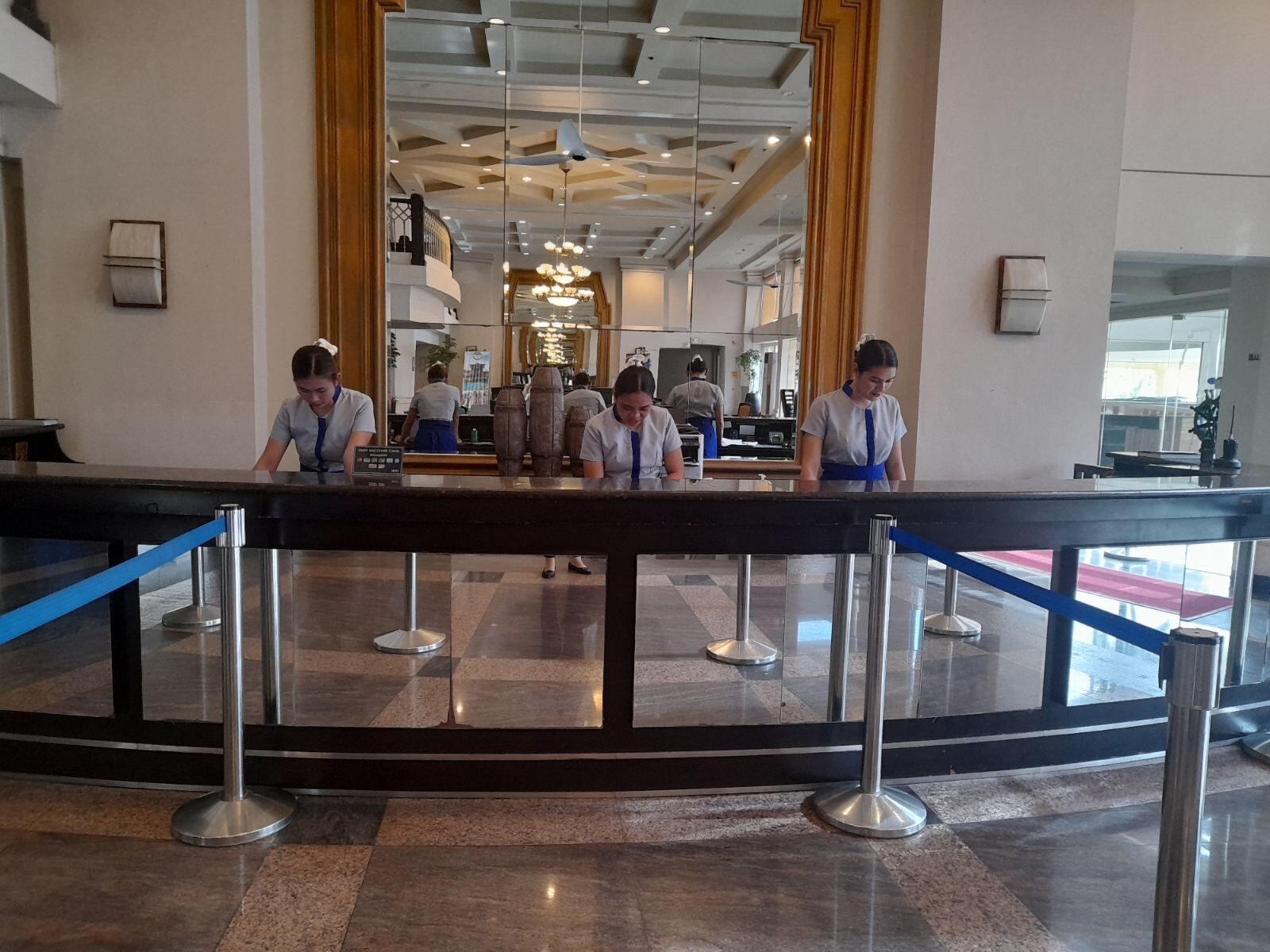 A reception area with a check-in counter, a glass barrier, and a tiled floor.