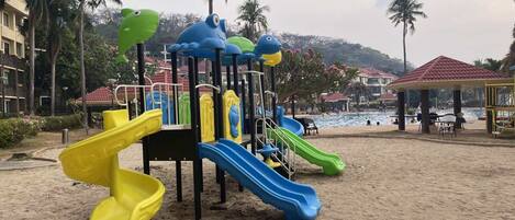 Un parque infantil en la playa con toboganes y estructuras para escalar.