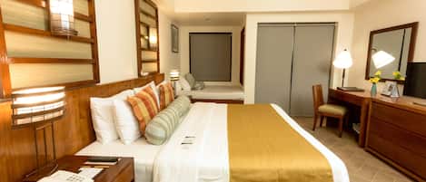 A hotel room with a bed, bedside table, desk, chair, and a wardrobe.