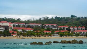 A coastal hotel with multiple buildings, a beach, and rocky outcrops.