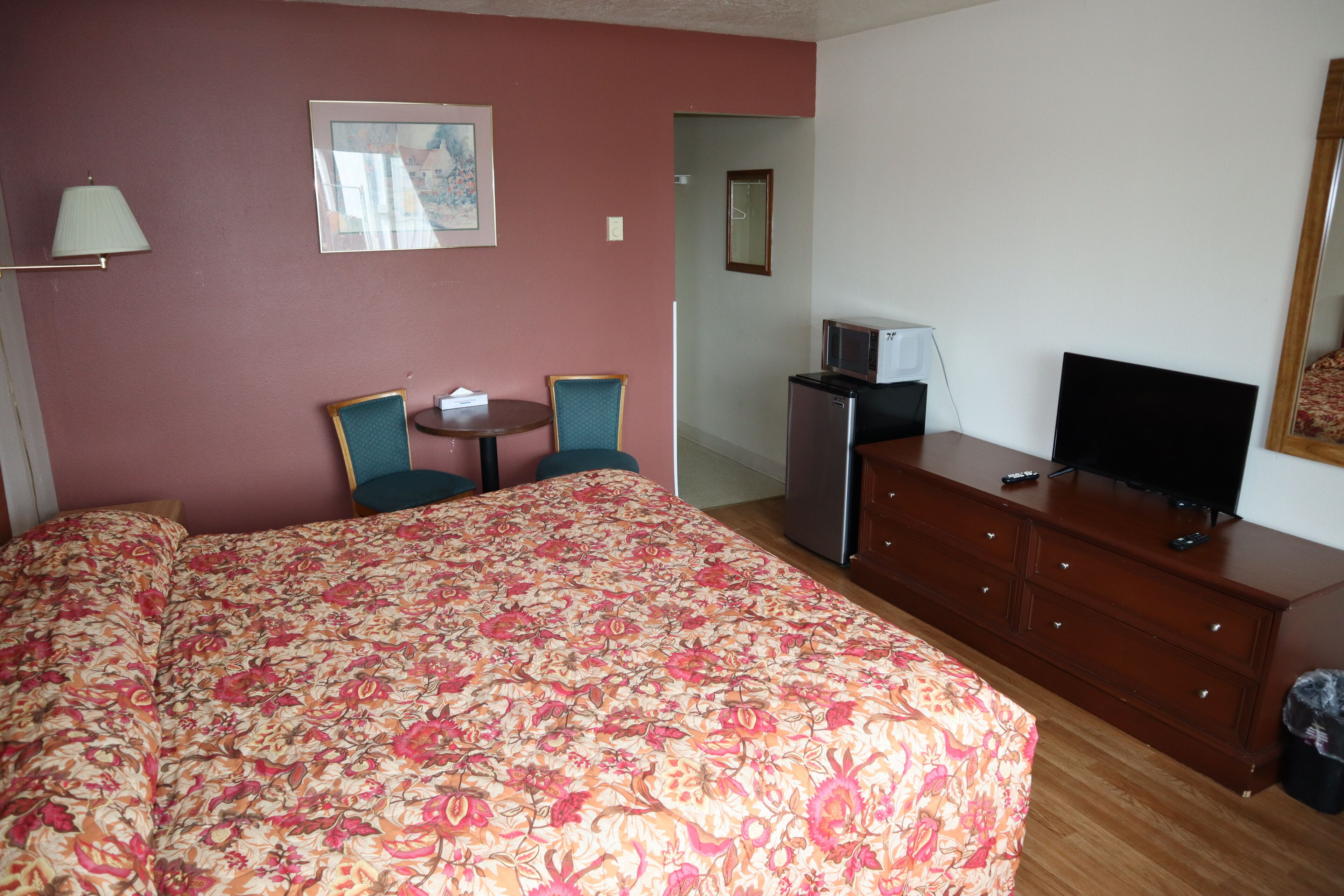 A hotel room with a large bed, a TV, a desk, and a chair.