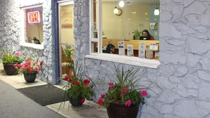 Un restaurante con fachada de piedra, un letrero abierto y plantas en macetas afuera.
