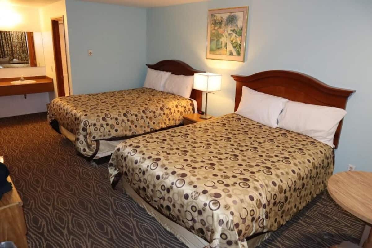 Ein Hotelzimmer mit zwei Betten, einem kleinen Tisch, einer Lampe und einem Bild an der Wand.