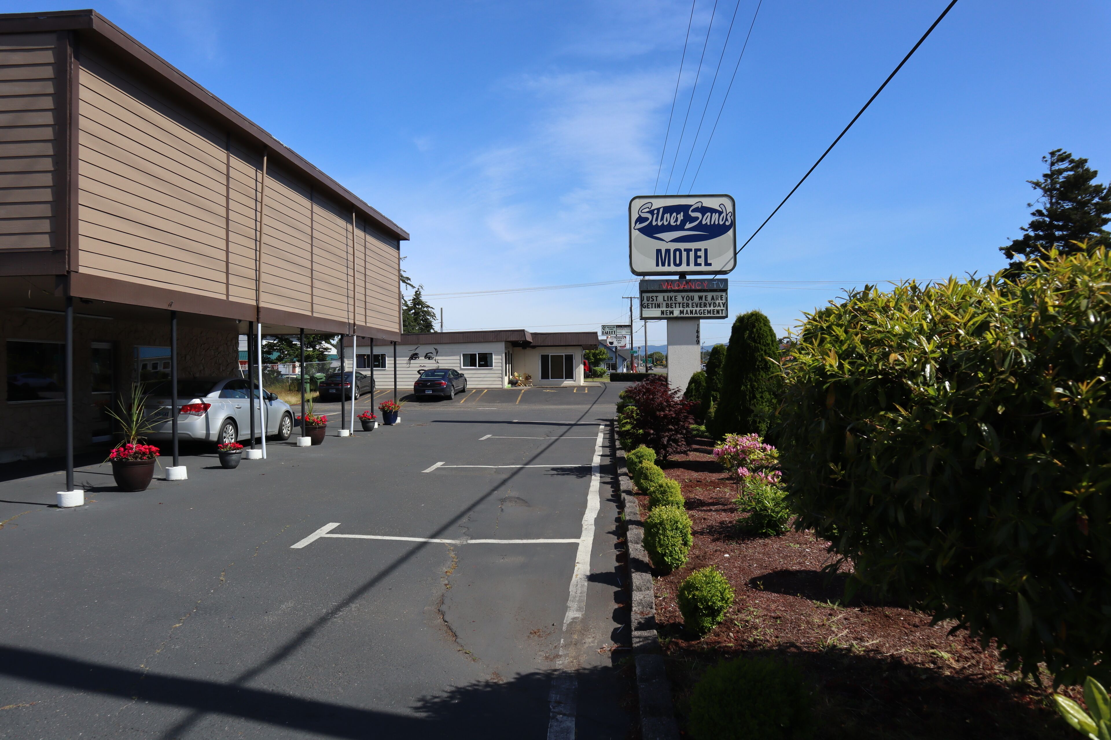 A motel with a signboard, parking lot, and a building facade.