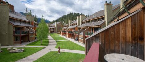 A row of wooden cabins with a paved walkway and a small tree in the center.