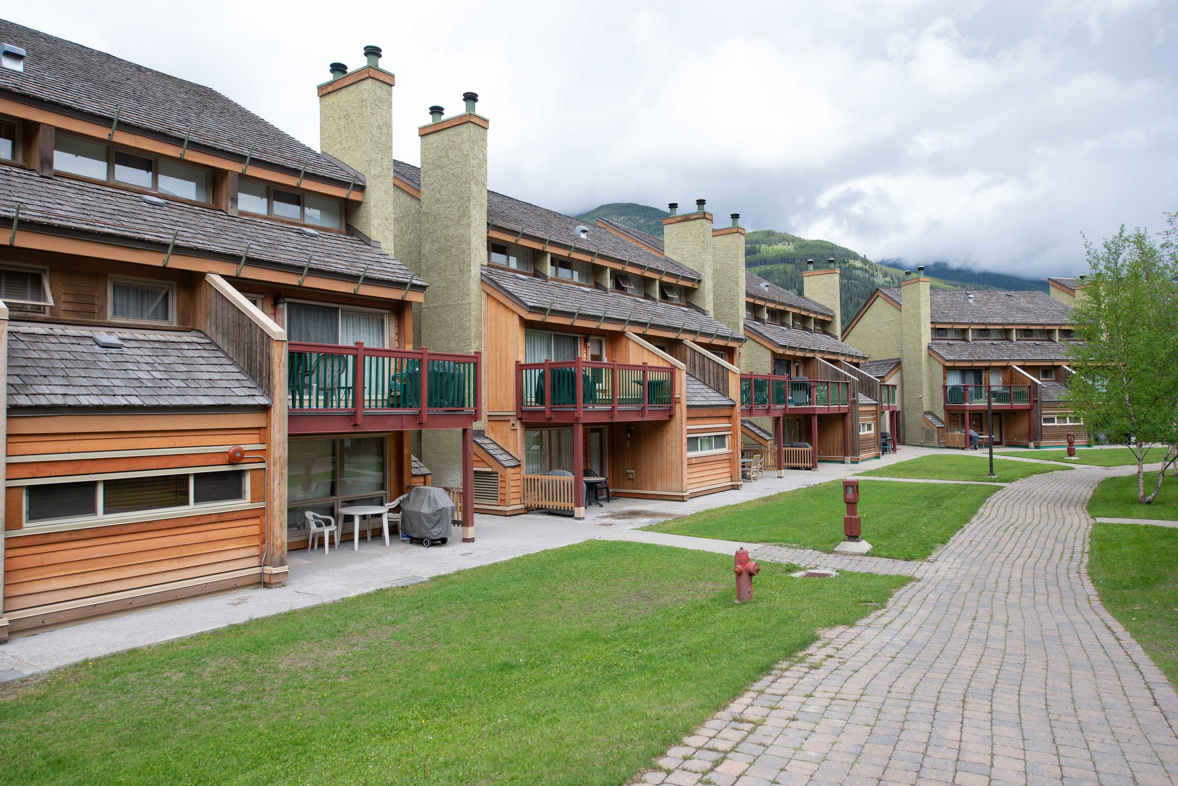 A row of wooden buildings with balconies, a fire hydrant, and a paved walkway.