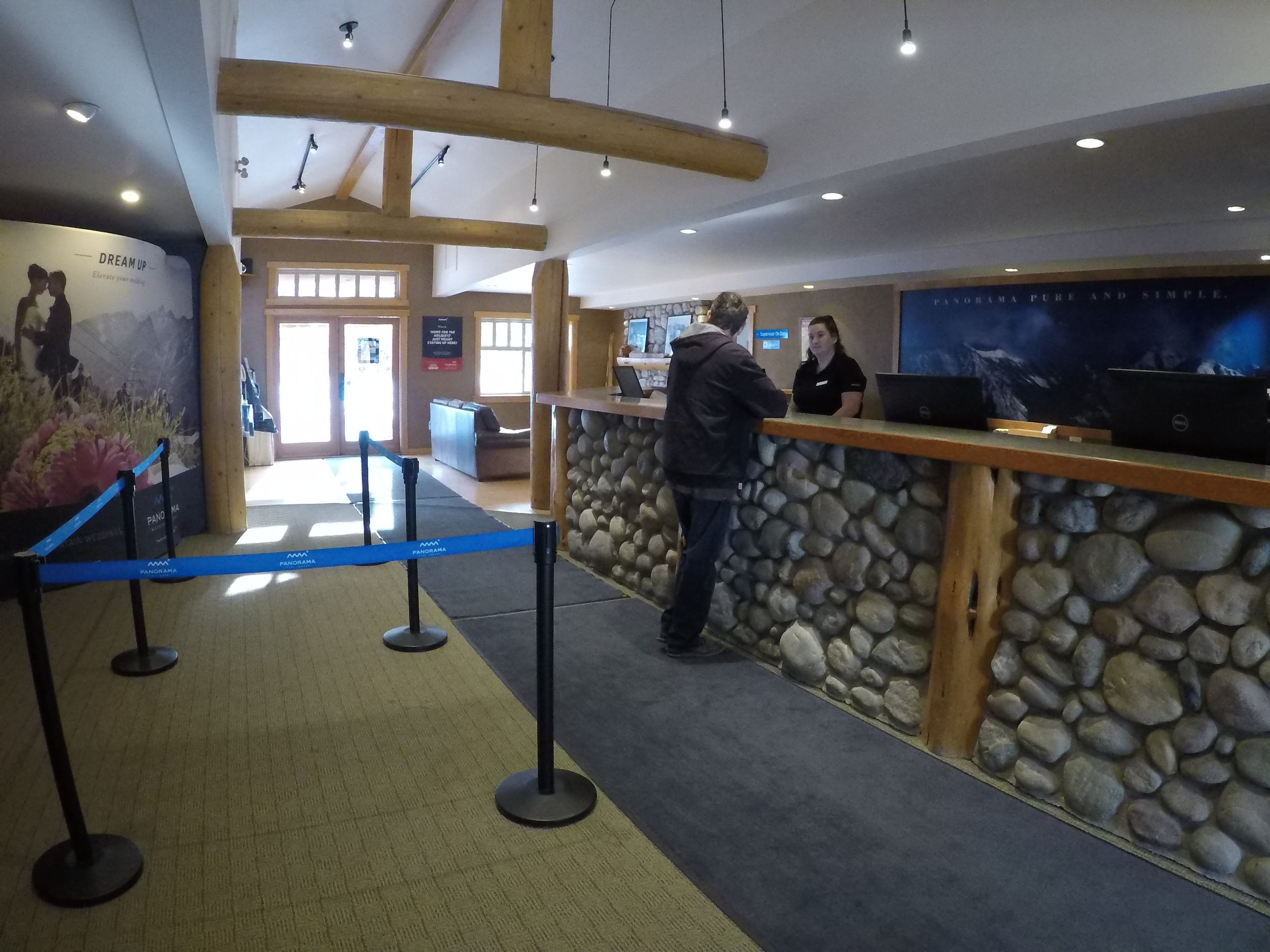 A reception area with a stone wall, wooden beams, and a blue barrier.