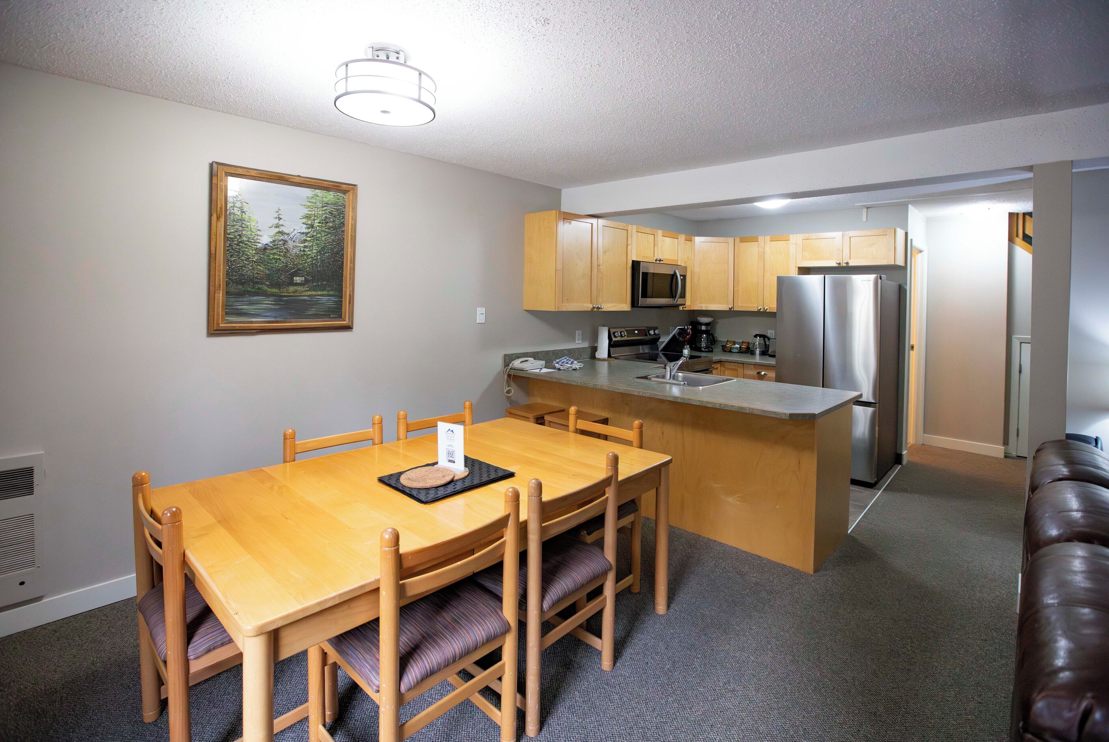 A compact kitchen with wooden cabinets, a stainless steel refrigerator, and a microwave.