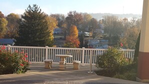 A covered outdoor area with a brick floor, white railing, and stone benches. - Paradise Inn & Suites (Towanda)