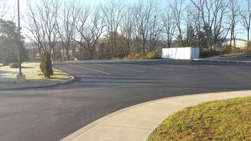A parking lot with clear lines, a sidewalk, and leafless trees.