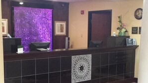 A reception area with a purple-lit wall, a tiled floor, and a clock on the wall. - Paradise Inn & Suites (Towanda)