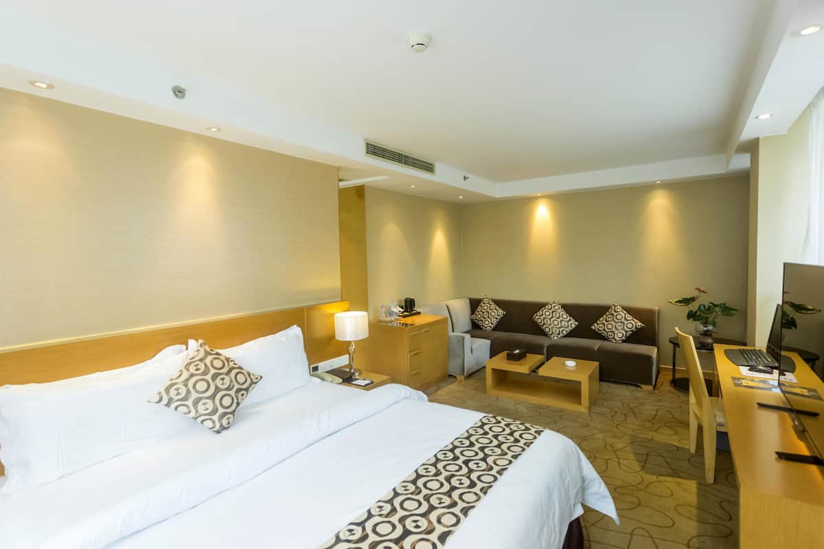 Une chambre d’hôtel avec un lit, un canapé, un bureau et une chaise.