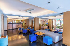 Un vestíbulo de hotel con zonas de estar, una recepción y un bar.
