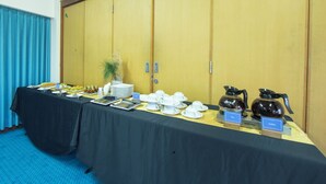 A conference room with a long table set for a meeting, equipped with coffee and tea stations, and a large wooden wardrobe in the background. - Kuta Beach Hotel (Kuta)