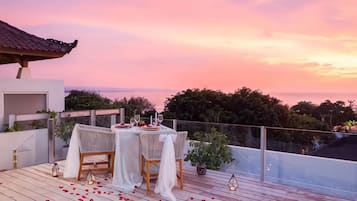 Un área de comedor al aire libre con una mesa lista para dos personas, con vista a un paisaje pintoresco.