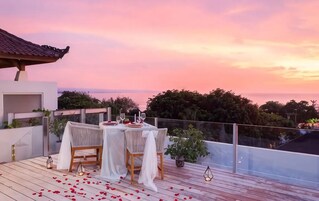 Un área de comedor al aire libre con una mesa lista para dos personas, con vista a un paisaje pintoresco.