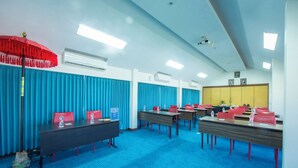 A conference room with blue carpeting, red chairs, and tables, equipped with air conditioning and ceiling lights. - Kuta Beach Hotel (Kuta)