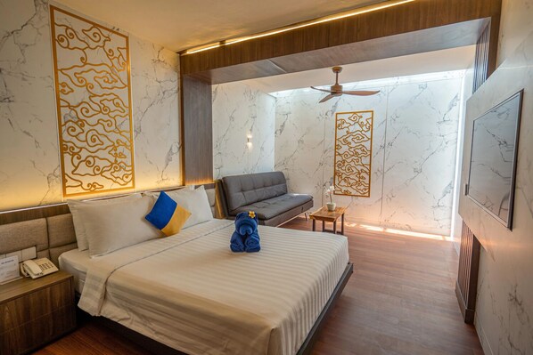 A modern hotel room with a large bed, a sofa, and a small table. - Kuta Beach Hotel (Kuta)