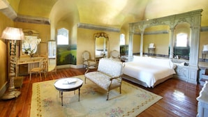 A spacious bedroom with a large bed, a sitting area with a table, and a decorative mirror. - Castillo de Arteaga (Gautegiz Arteaga)