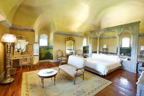 A spacious bedroom with a large bed, a sitting area with a table, and a decorative mirror. - Castillo de Arteaga (Gautegiz Arteaga)