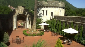 A courtyard with a stone building, palm trees, and outdoor seating. - Castillo de Arteaga (Gautegiz Arteaga)