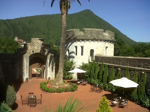 A courtyard with a stone building, palm trees, and outdoor seating. - Castillo de Arteaga (Gautegiz Arteaga)