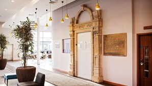 A lobby with a stone archway labeled "Electricity Works" and a plaque detailing historical information. There are potted plants, seating areas, and hanging pendant lights. - DoubleTree by Hilton Lincoln (Lincoln)