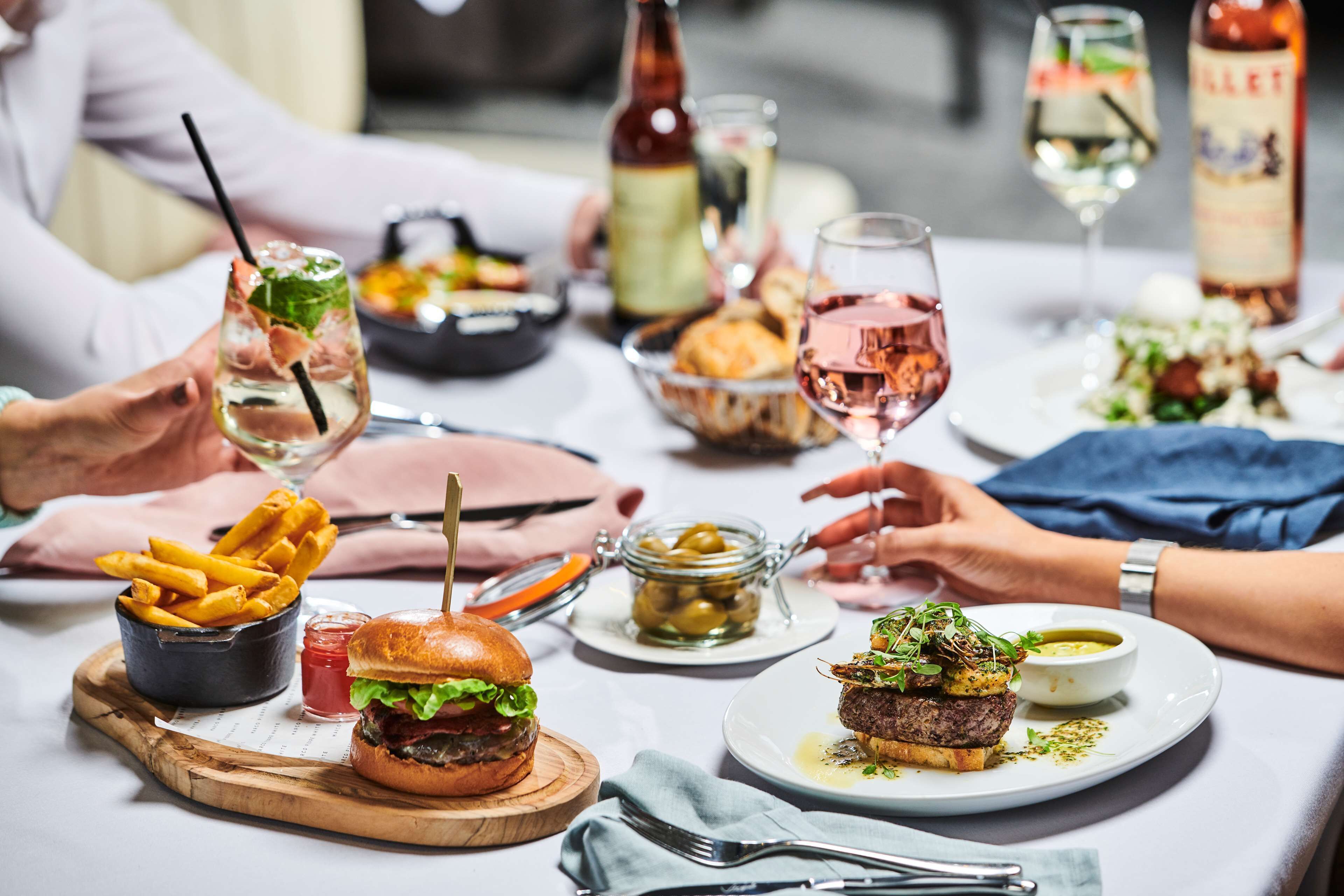 A dining table with various dishes, including burgers, fries, and a salad.