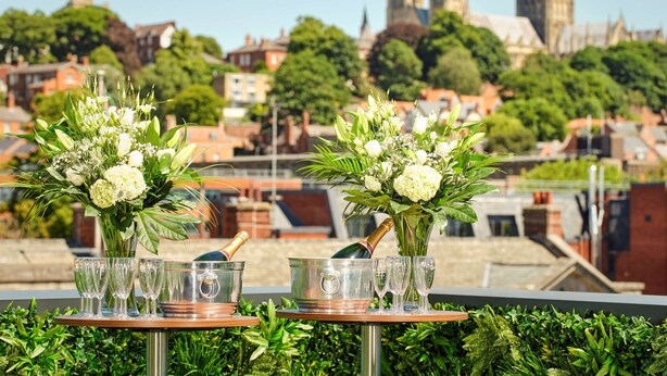 A table with champagne flutes and a bottle, set against a cityscape with historic buildings. - DoubleTree by Hilton Lincoln (Lincoln)