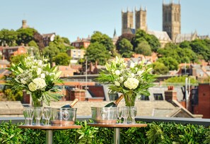 A table with champagne flutes and a bottle, set against a cityscape with historic buildings. - DoubleTree by Hilton Lincoln (Lincoln)