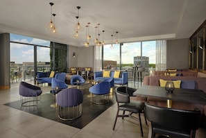 A modern lounge area with seating, a dining table, and pendant lighting. - DoubleTree by Hilton Lincoln (Lincoln)