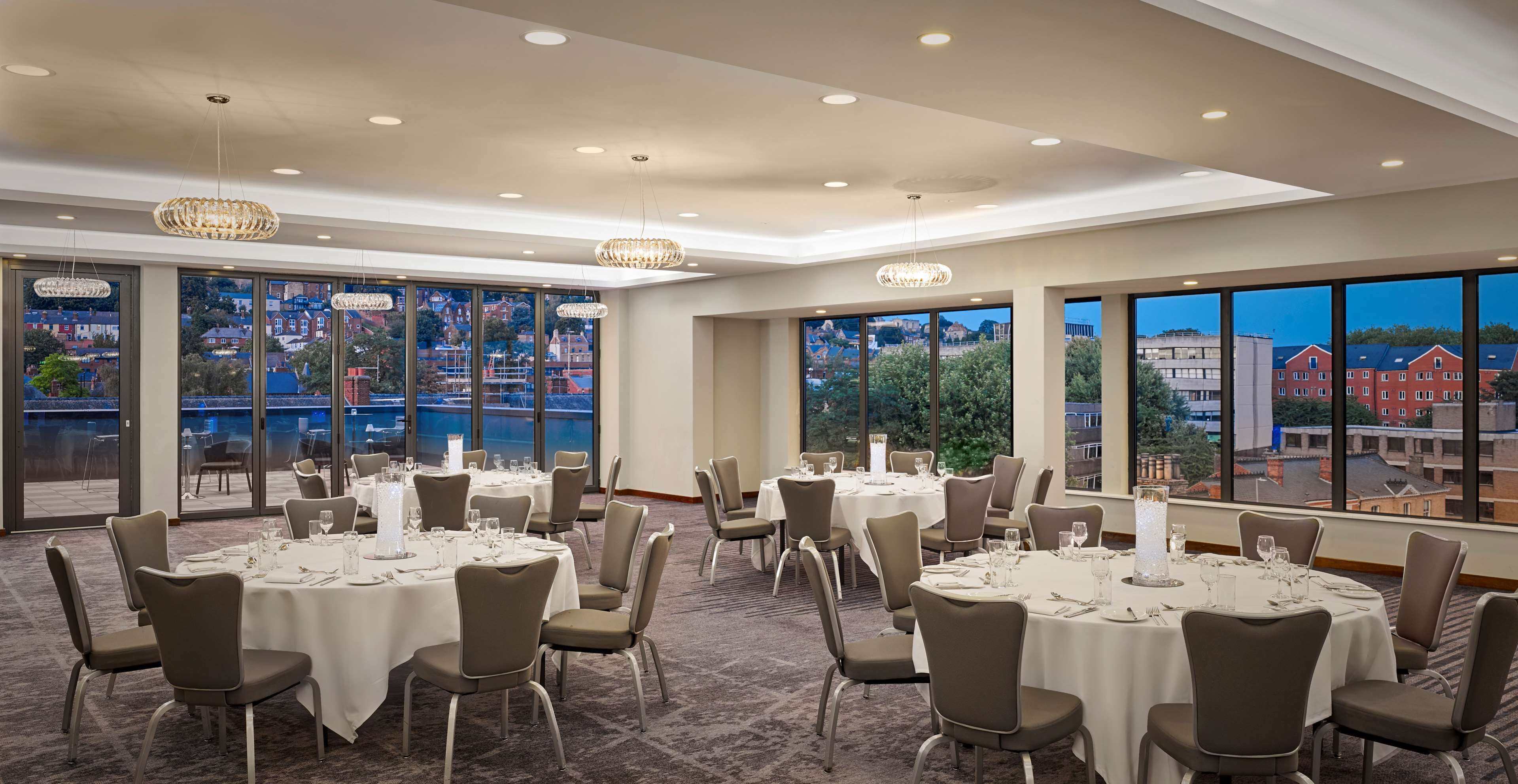 A conference room with round tables, chairs, and chandeliers.