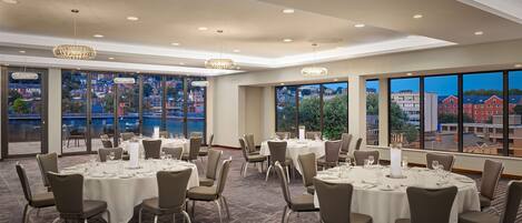 A conference room with round tables, chairs, and chandeliers.