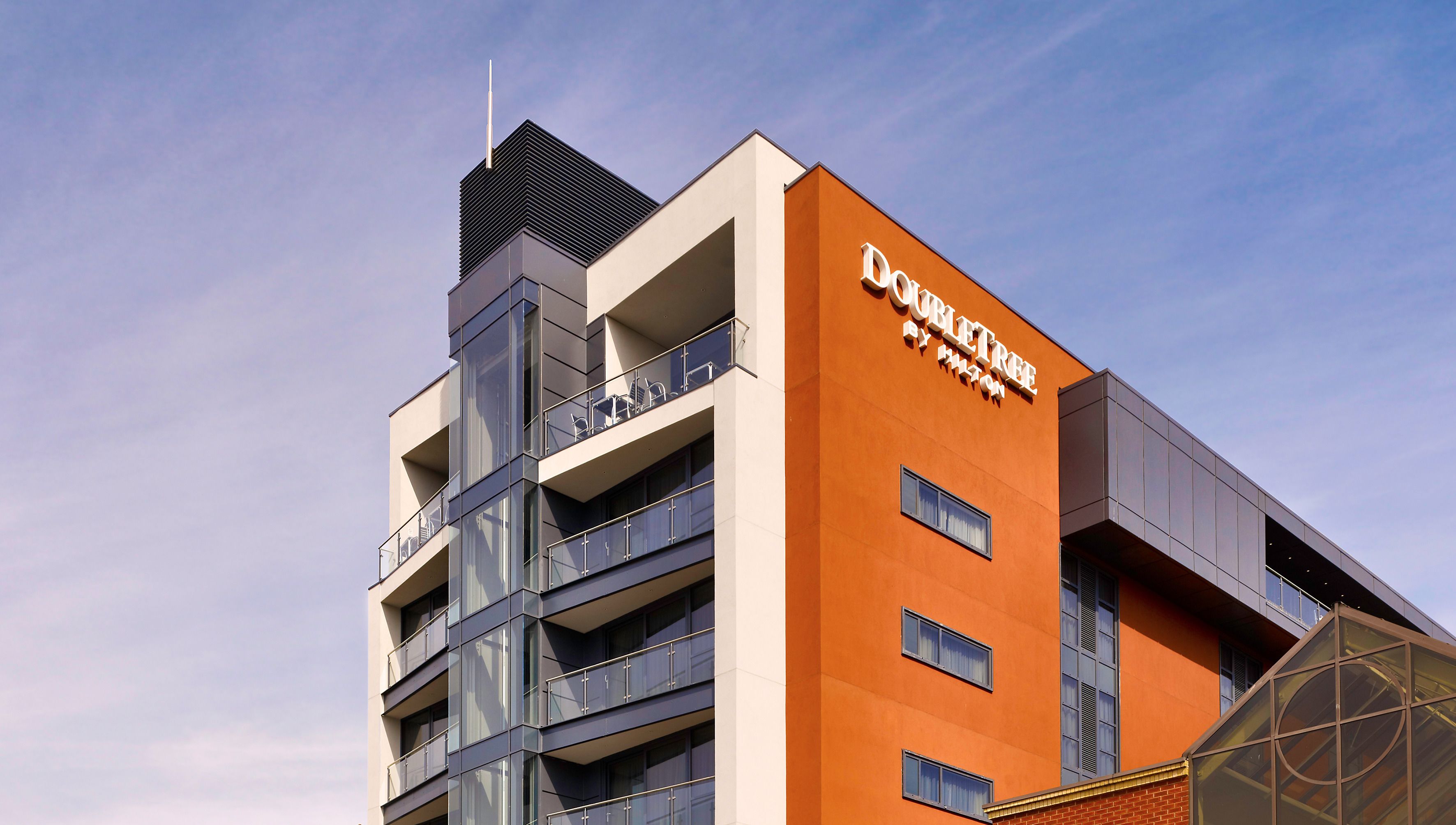Un moderno edificio de hotel con varios balcones y un letrero llamativo que dice "Olivetree Hotel".