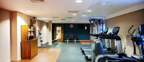 A gym with treadmills, elliptical machines, and a weight rack.