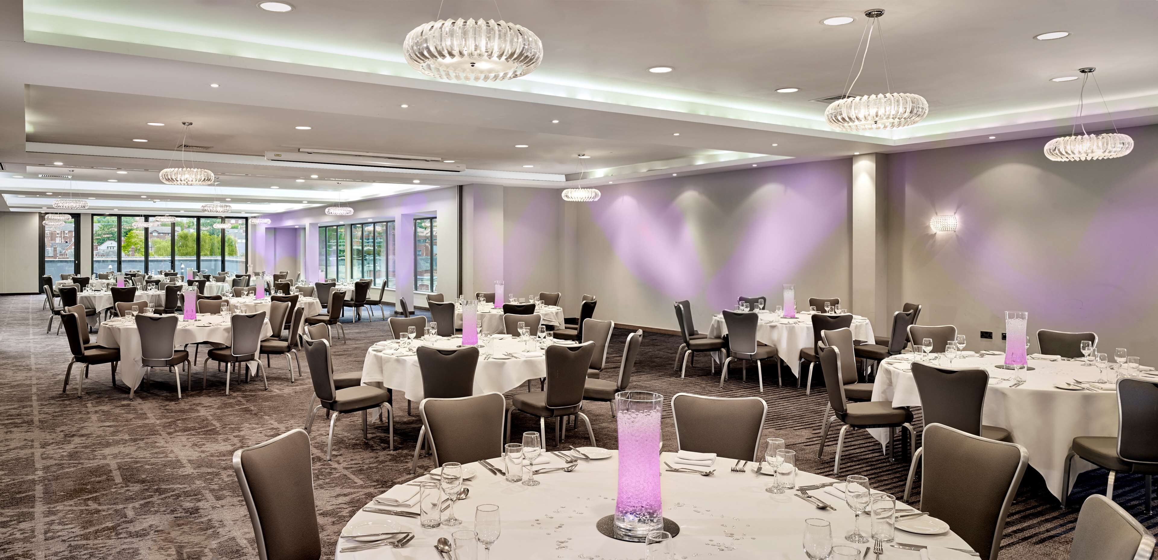 Un salón de banquetes con mesas redondas, sillas y candelabros.