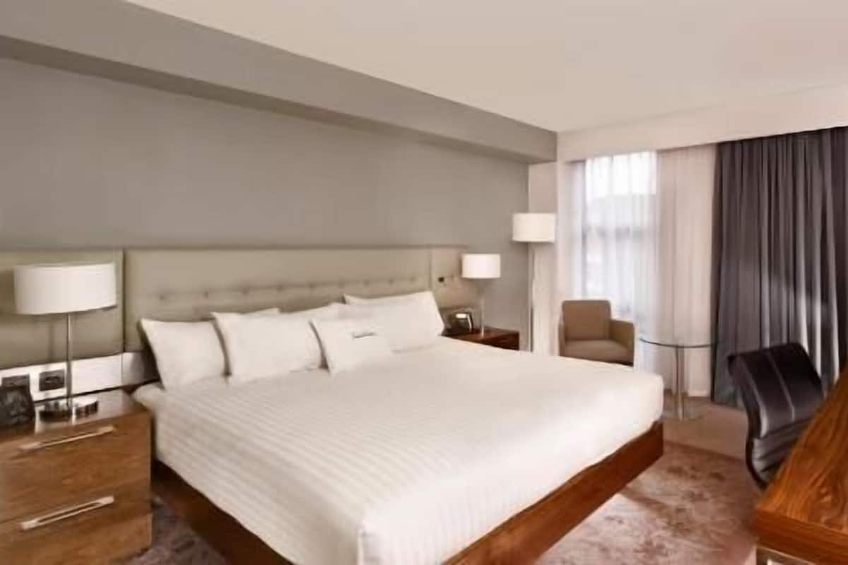 A hotel room with a large bed, bedside tables, a desk, and a chair.